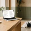 Le chapitre 1 du Veterinary Prompt Pack ouvert sur un portable dans une clinique vétérinaire, un border collie au repos à côté — AJNEXA