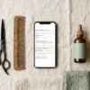 Une vraie page du Hair Salon Prompt Pack sur un téléphone, parmi des outils de coiffure — AJNEXA