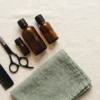 Ciseaux de coiffure, peigne et flacons ambrés sur du lin crème — AJNEXA Hair Salon Prompt Pack