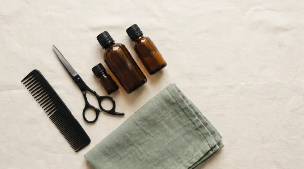 Ciseaux de coiffure, peigne et flacons ambrés sur du lin crème — AJNEXA Hair Salon Prompt Pack